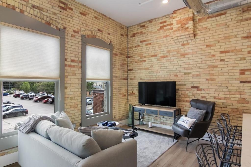 a living room with a brick wall and a television at Golden Lofts Unit 1 Downtown Traverse City 1BD 1BA in Traverse City