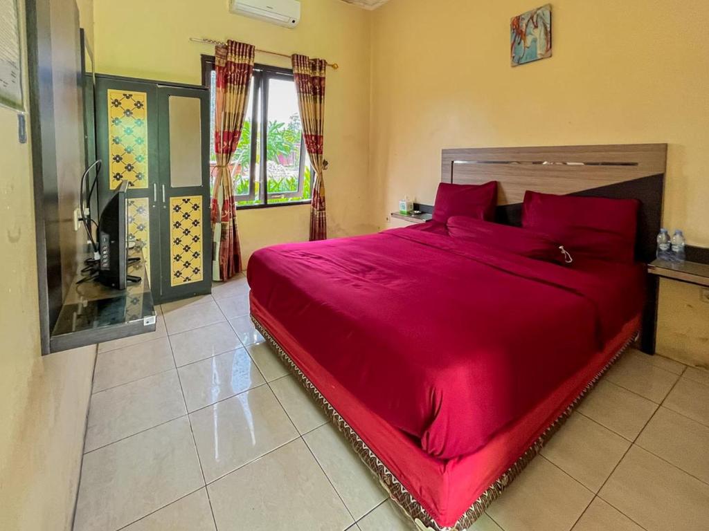 SampitにあるGreenville Hotel Mitra RedDoorzのベッドルーム1室(大型ベッド1台、赤い枕付)