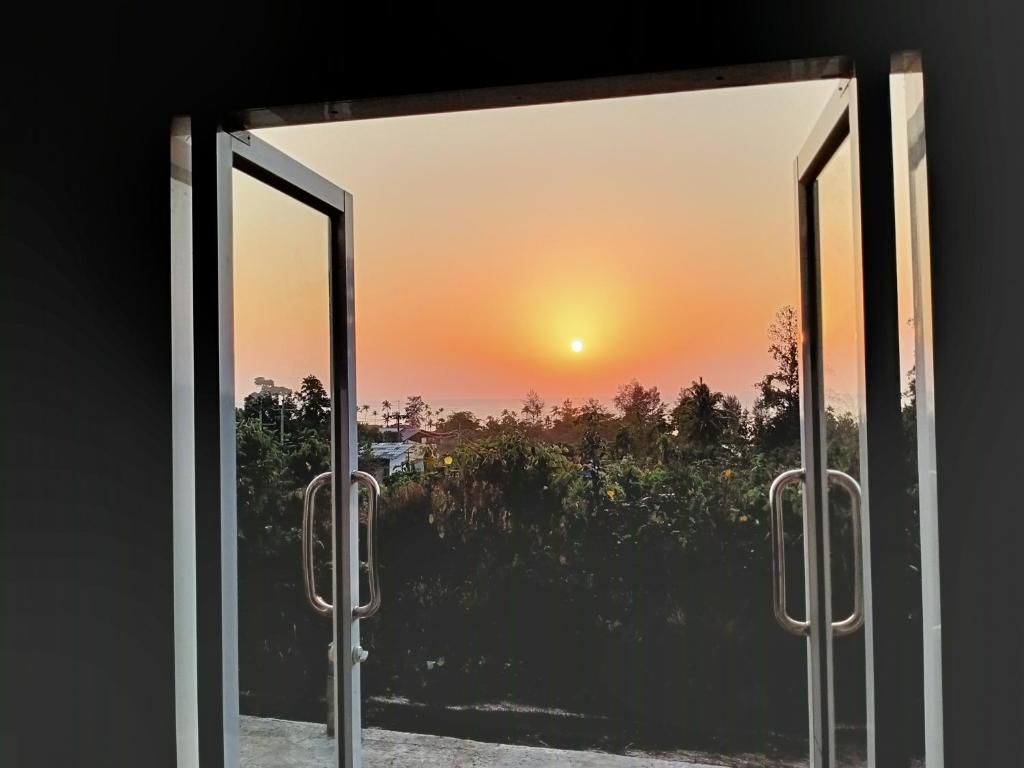 una ventana abierta con vistas a la puesta de sol en Lanta Farita House, en Phra Ae beach