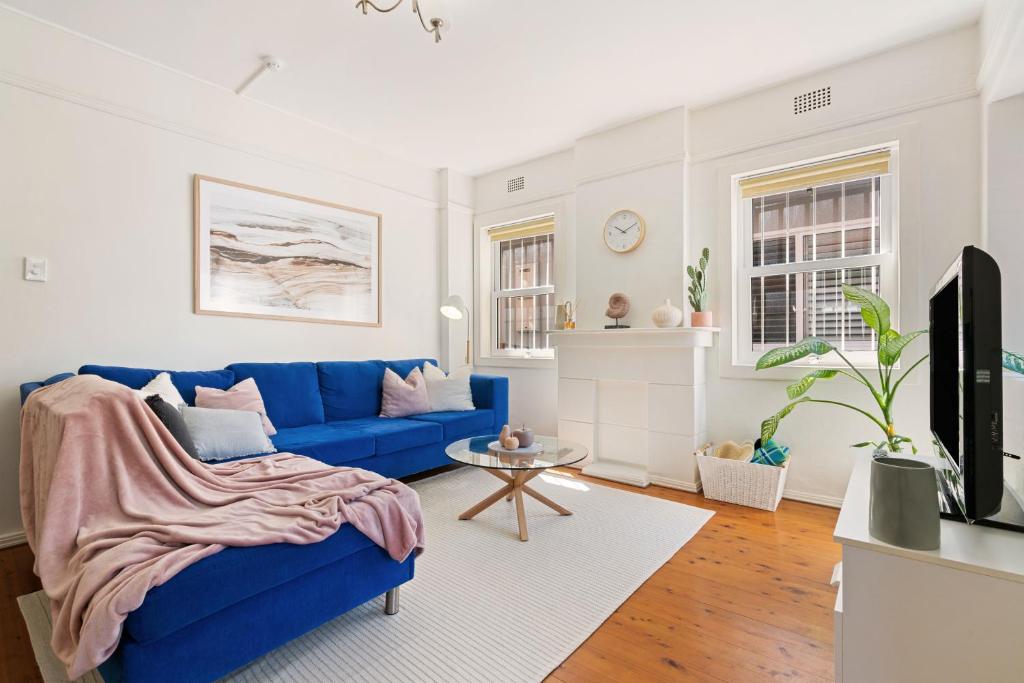 a living room with a blue couch and a tv at Beach-side North Bondi in Sydney