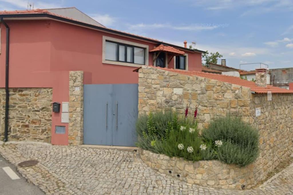 a red house with a blue door and a stone wall at A Casa da Carmita in Pedrógão Grande