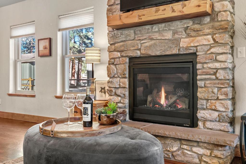 a living room with a fireplace and a table with wine glasses at Black Bear Cabin with Hot Tub in Woodland Park