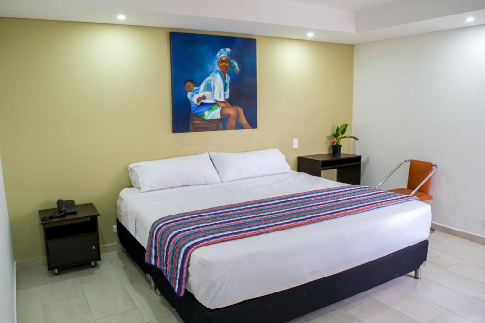 a bedroom with a large bed with a painting on the wall at HOTEL OASIS in Rionegro