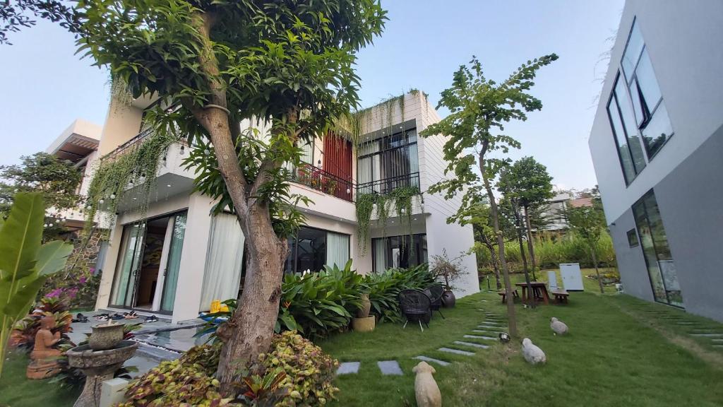 una casa con un árbol delante de un patio en Sun Villa- Flamingo Venus Đại Lải, en Vĩnh Phúc