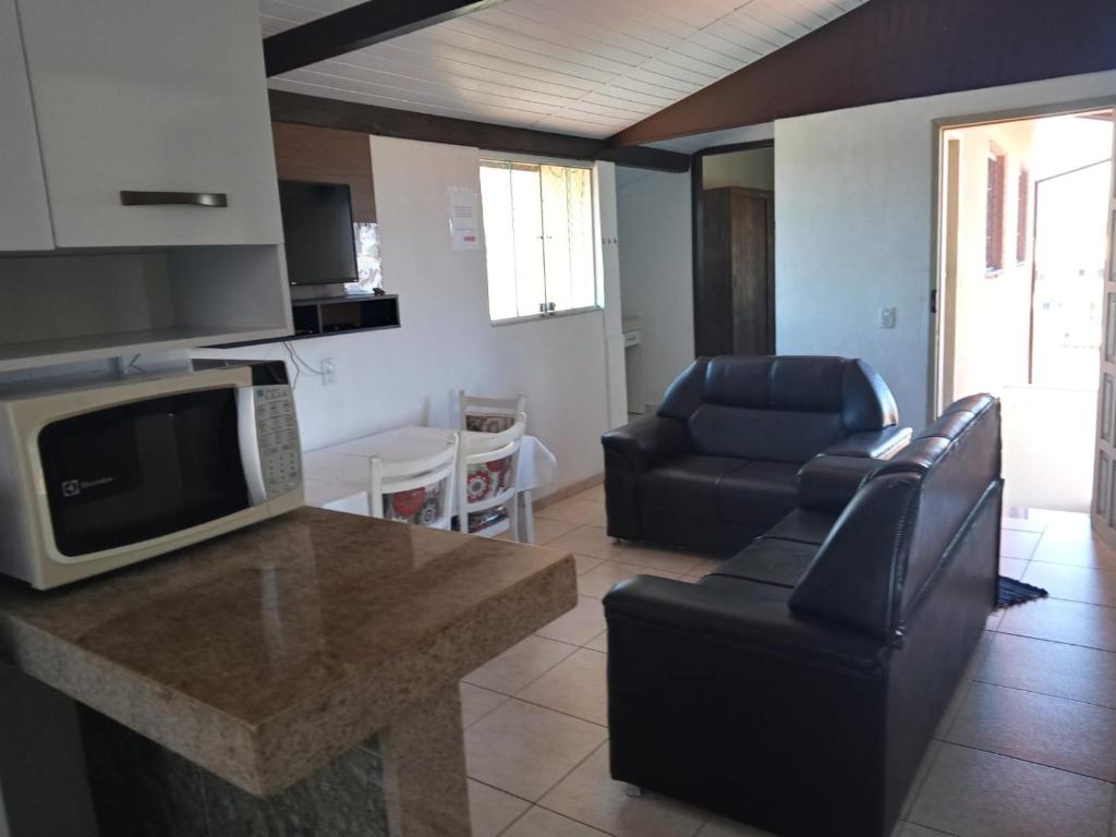 a living room with a kitchen with a counter and chairs at OTIMO APARTAMENTO EM JACARAIPE ES ! in Serra