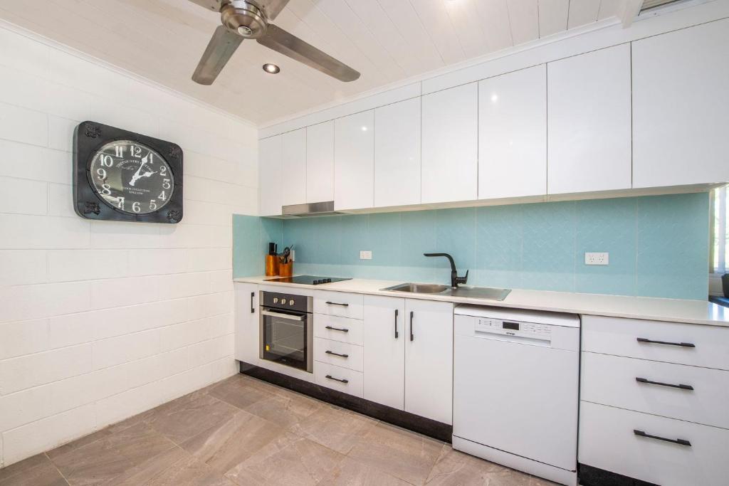 a kitchen with white cabinets and a clock on the wall at Island View Apt 1 in Arcadia