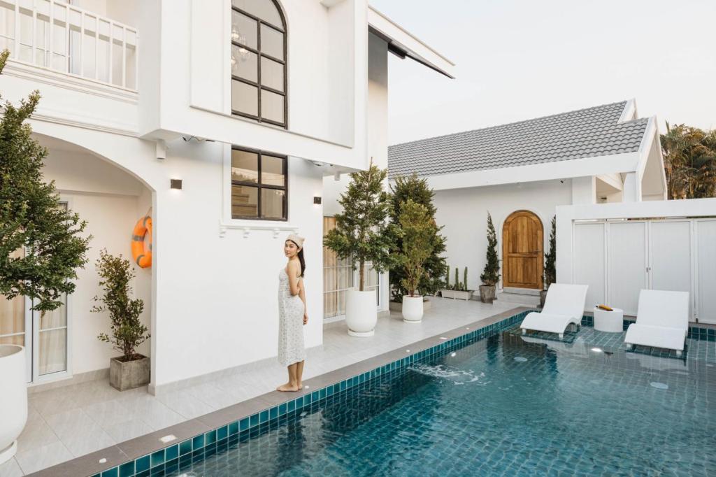 a woman standing next to a swimming pool in a house at Zenzen Pool Villa in Chiang Mai