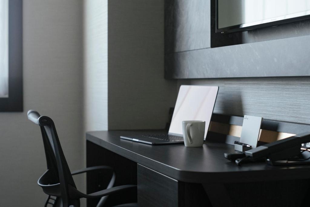 a desk with a laptop and a cup on it at Hotel JAL City Haneda Tokyo in Tokyo