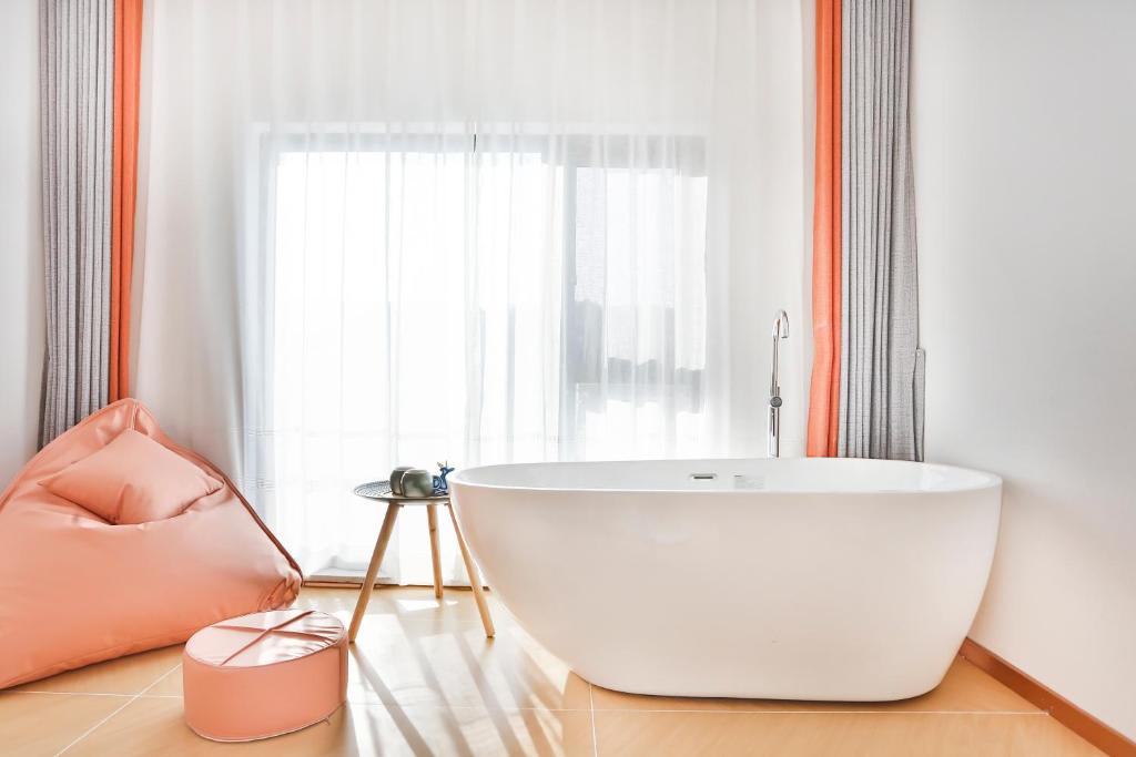 a bathroom with a large white tub in front of a window at Flower Whisperer Homestay Tianmenshan Store free airport and station pick-up in Zhangjiajie
