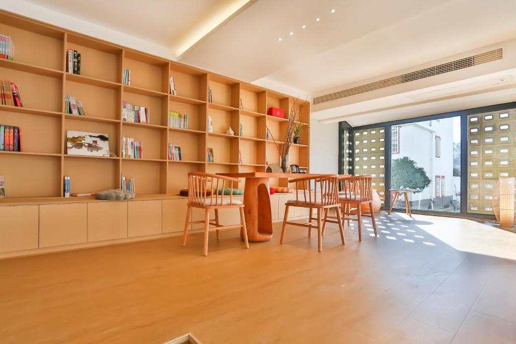 a living room with a table and chairs and bookshelves at Flower Whisperer Homestay Tianmenshan Store free airport and station pick-up in Zhangjiajie