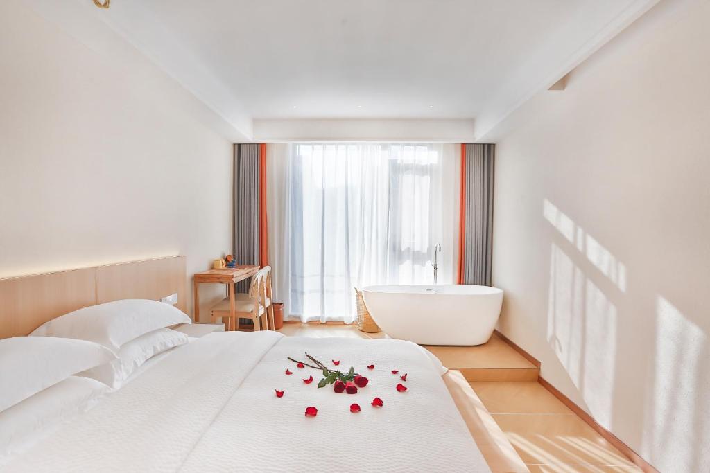 a bedroom with a white bed and a bath tub at Flower Whisperer Homestay Tianmenshan Store free airport and station pick-up in Zhangjiajie