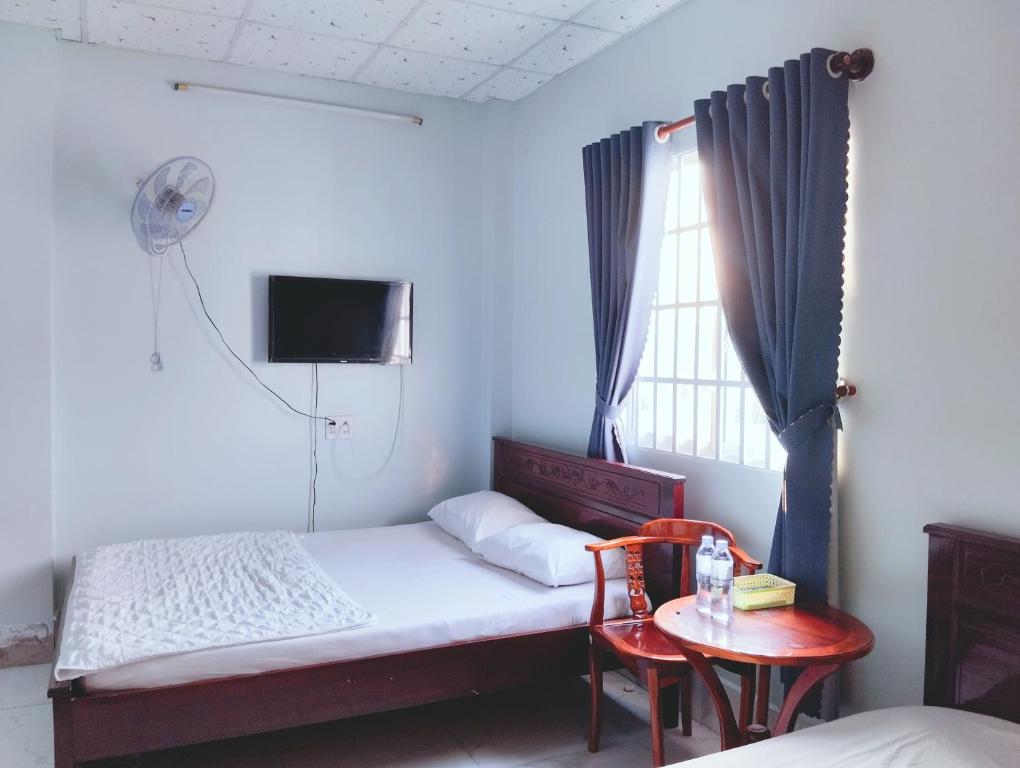 1 dormitorio con cama, mesa y ventana en Nhà nghỉ Thành Lợi, en Ấp Rạch Mẹo