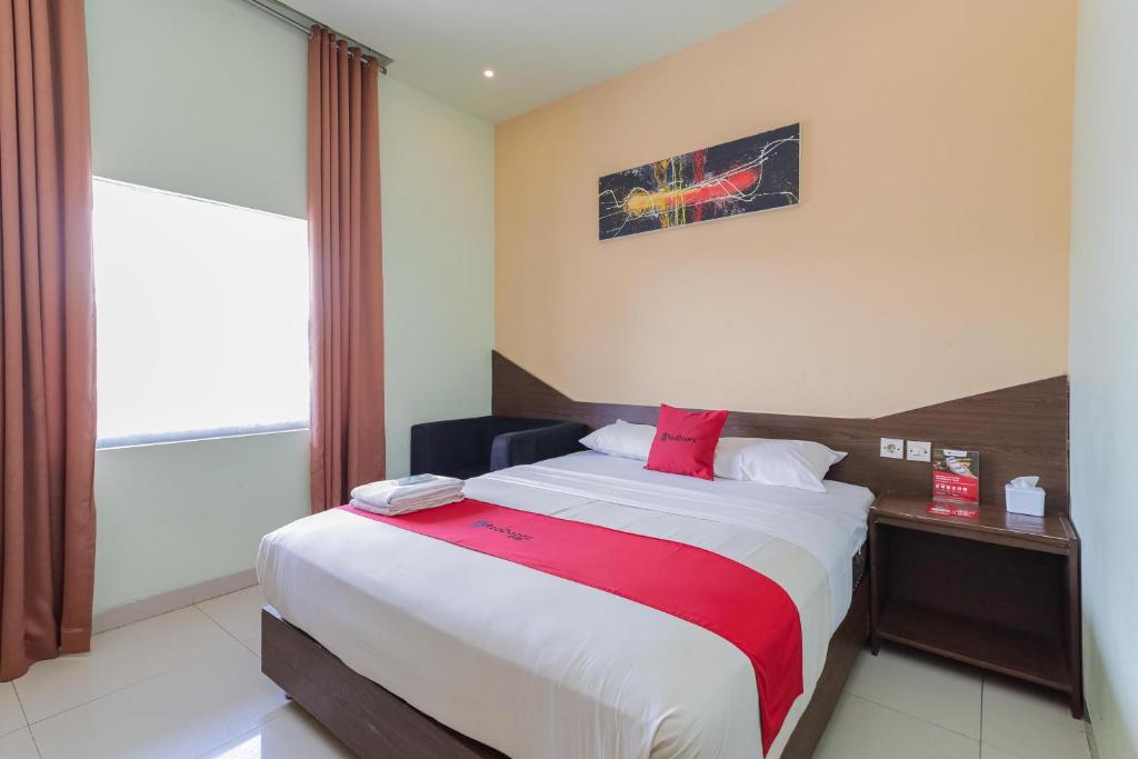 een slaapkamer met een groot bed en een rode deken bij RedDoorz near Alun Alun Madiun in Madiun