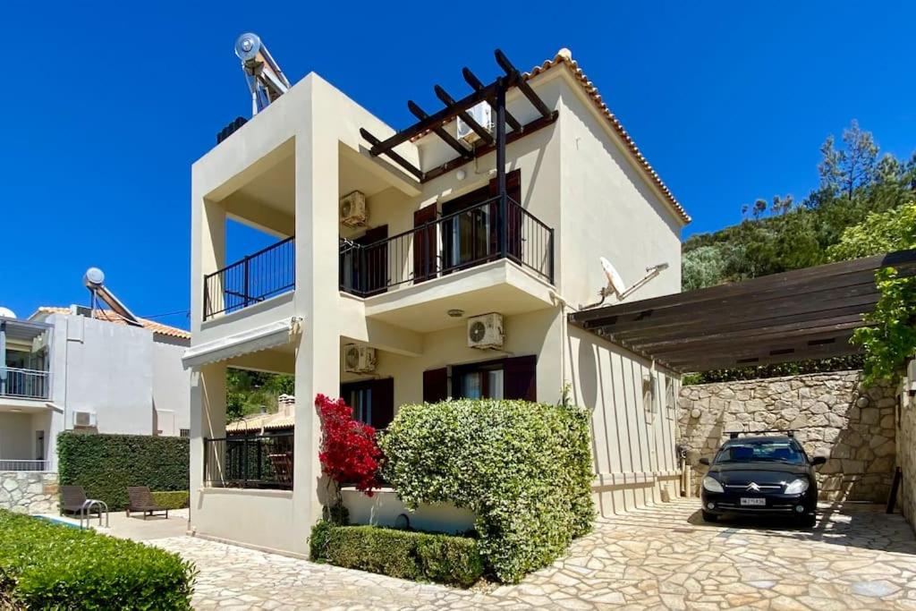 a white house with a car parked in front of it at Villa Seashell, Private Pool and Magnficent View in Ravdhoúkha