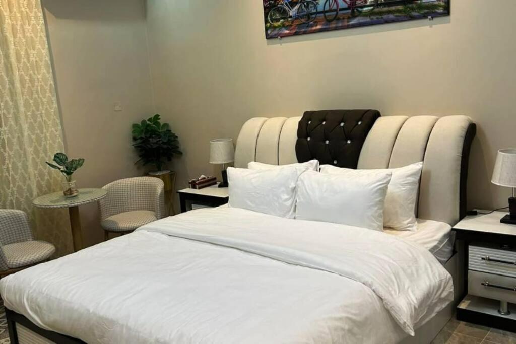 1 dormitorio con 1 cama blanca grande y cabecero grande en غرفة صغيرة ساحرة, en Riad