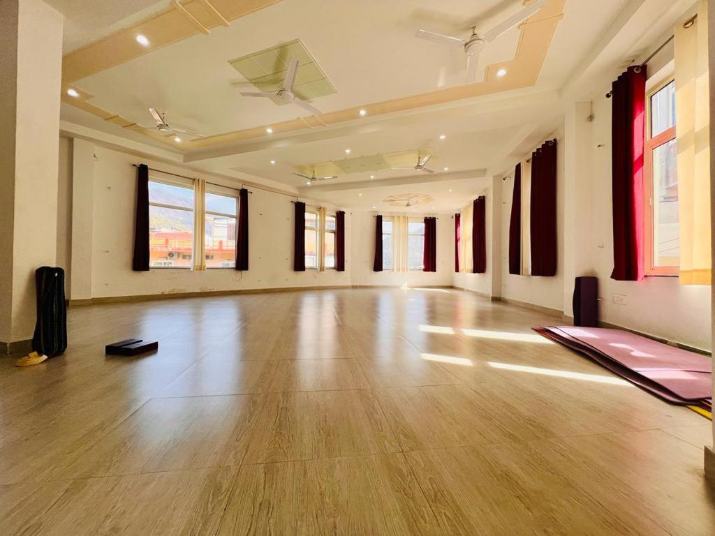 an empty room with a wooden floor and windows at The Ajna in Rishīkesh