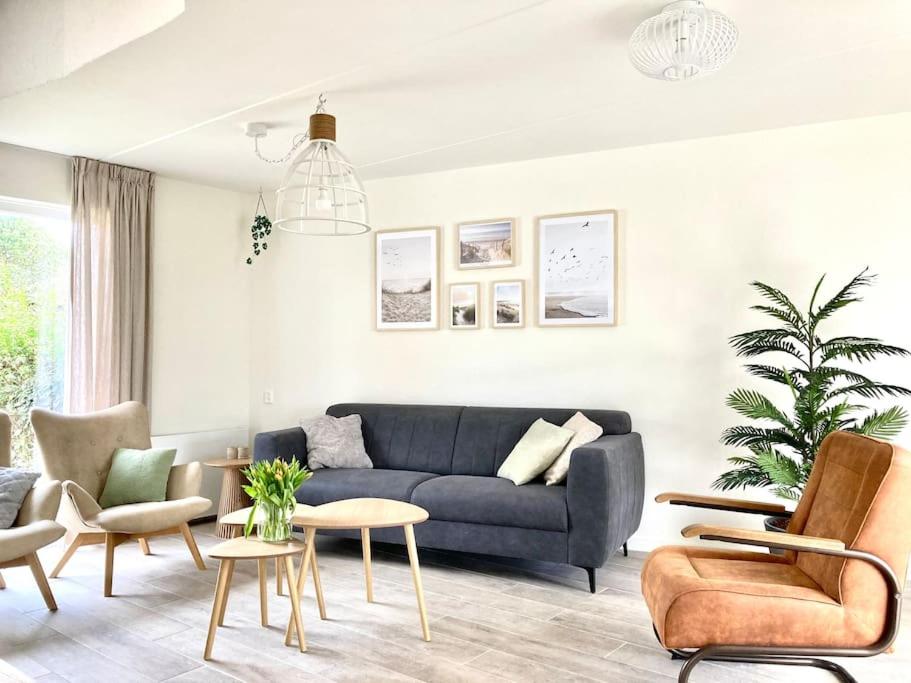 Maralong Noordwijk في نوردفيك: غرفة معيشة مع أريكة وكراسي زرقاء