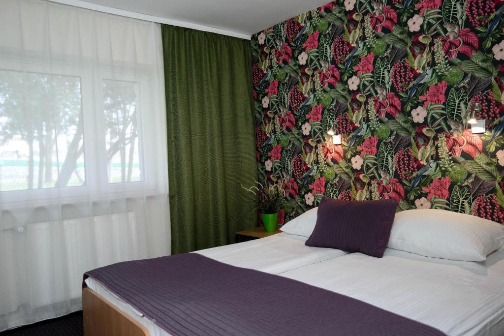 1 dormitorio con cama y pared de flores en Hotel George, en Nadarzyn