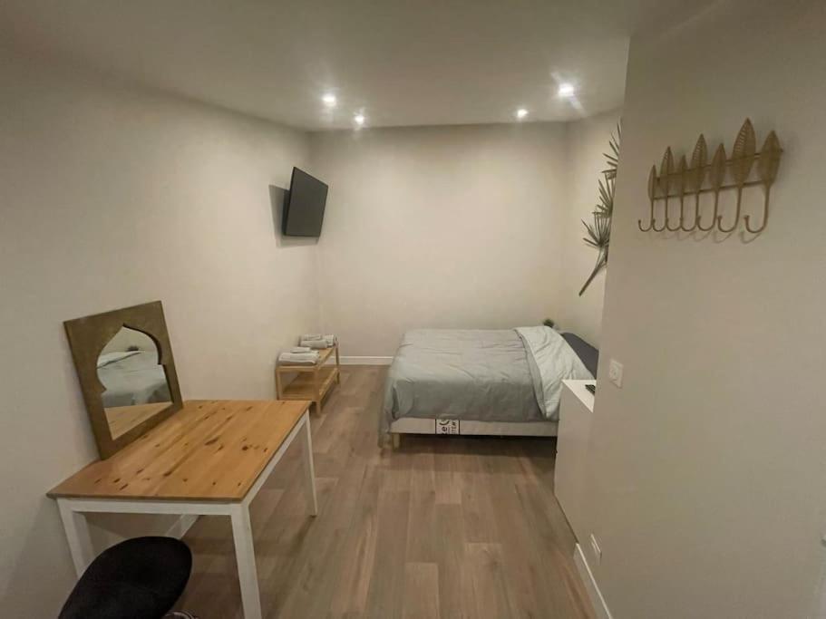 Schlafzimmer mit einem Bett, einem Tisch und einem Spiegel in der Unterkunft Studio indépendant - CDG, Paris,Disney,Astérix in Arnouville-lès-Gonesse