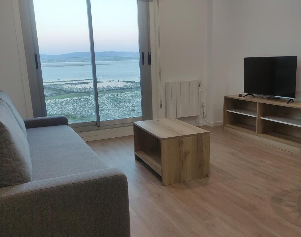 a living room with a couch and a tv and a table at Apartamentos O Grove Awa Bay in O Grove