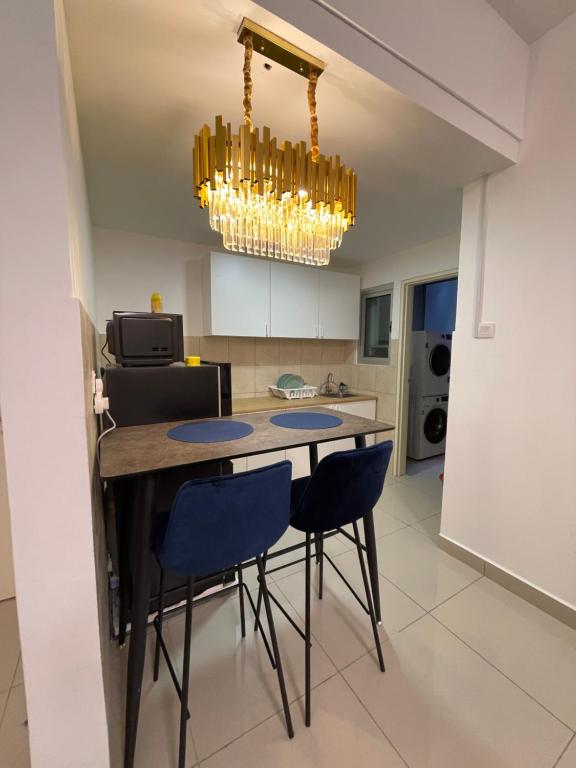 a kitchen with a table and chairs and a chandelier at Premium Service Appartment in Seri Kembangan