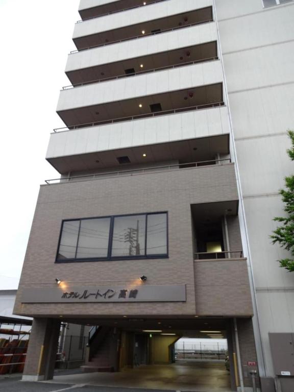 un edificio alto con un perro en el balcón en Hotel Route-Inn Takasaki Eki Nishiguchi, en Takasaki