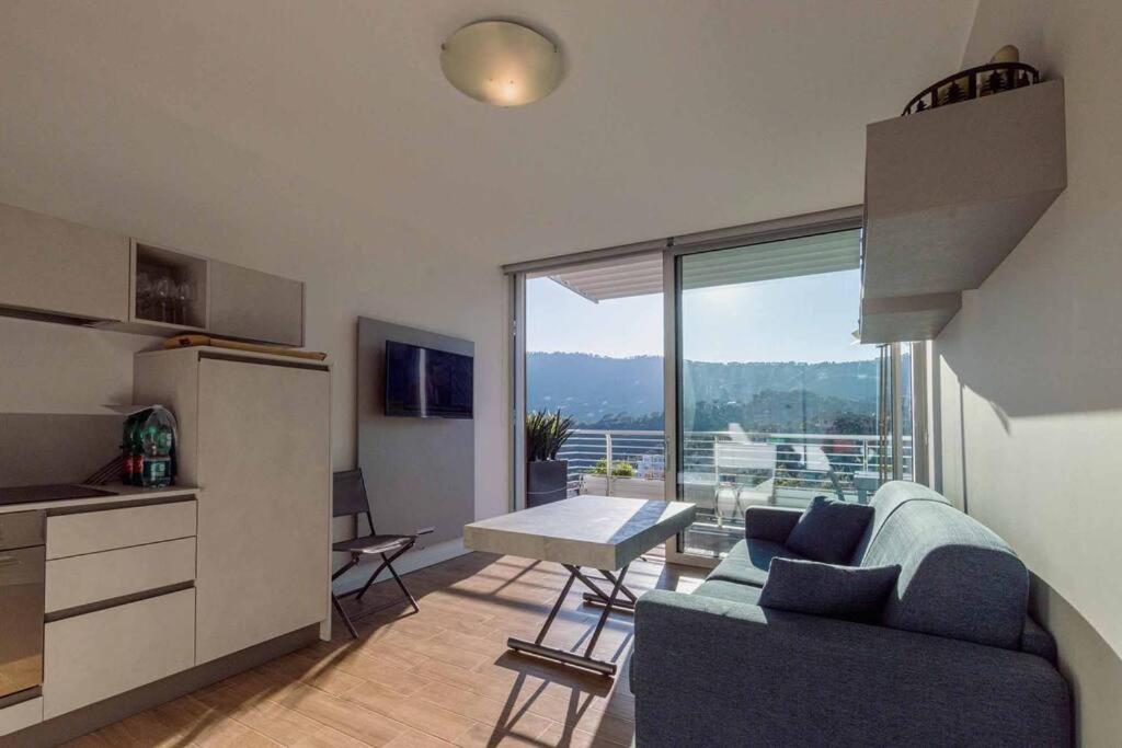 a living room with a couch and a table and a kitchen at Exclusive Apartment Alassio with sea view in Alassio