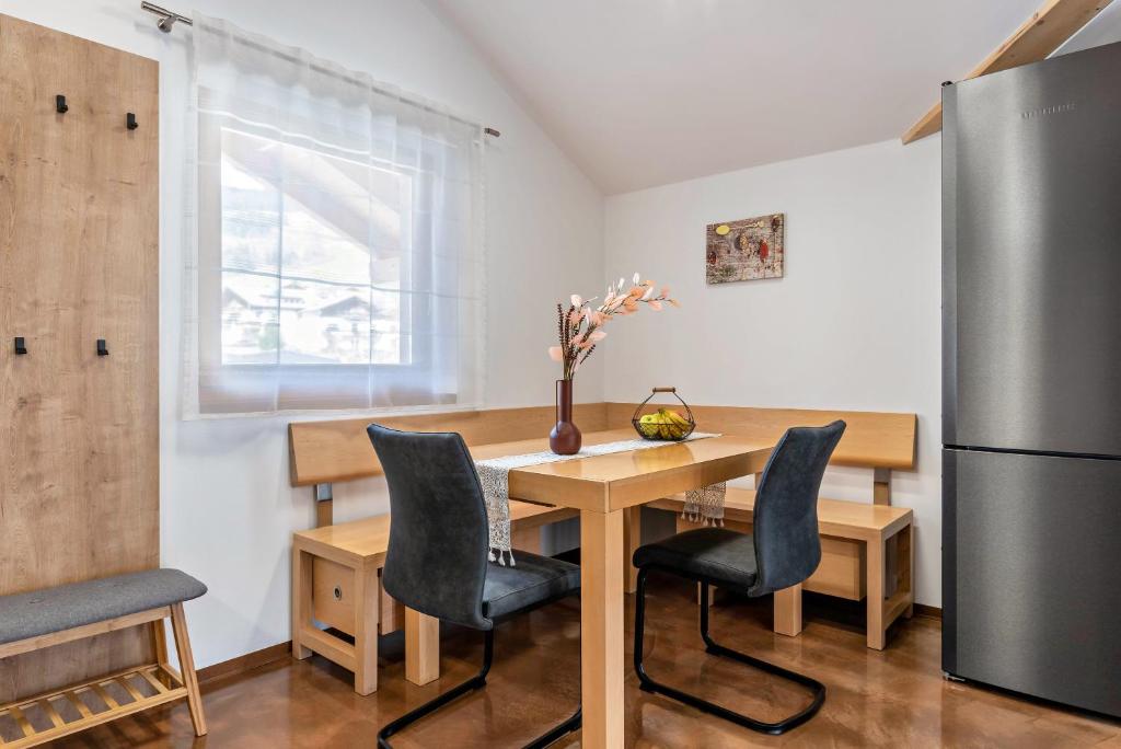 eine Küche mit einem Holztisch mit Stühlen und einem Kühlschrank in der Unterkunft Trojer Apartment 3 in Sarntal