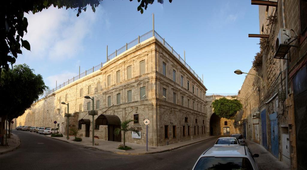 a large stone building with cars parked on a street at Akkotel-Boutique hotel in &lsquo;Akko