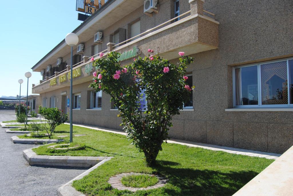 un arbusto con flores rosas delante de un edificio en Hotel Vista Nevada, en Darro