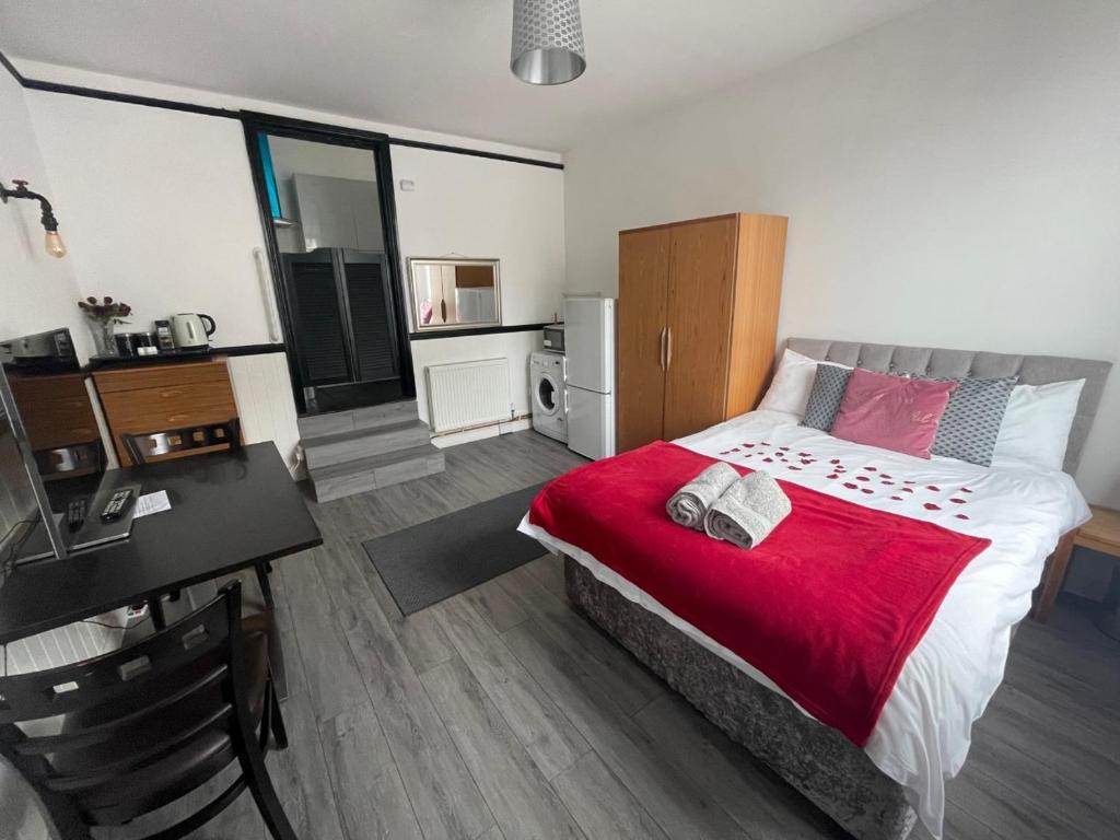 um quarto com uma cama com um cobertor vermelho e uma secretária em Modern Studio with Free Parking near sea-station-shops em Portslade