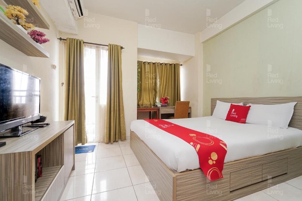 a bedroom with a bed and a flat screen tv at RedLiving Apartemen Margonda Residence 4 - Si Boy in Kemirimuka Tiga