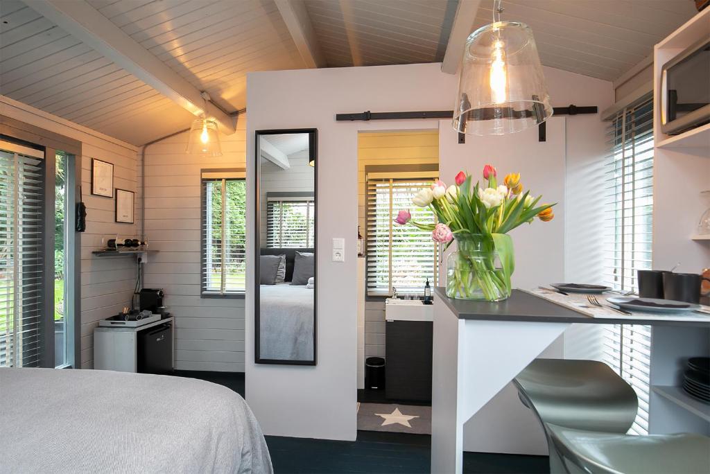 een slaapkamer met een bureau en een vaas met bloemen bij Tiny House Boatshed in Heemstede