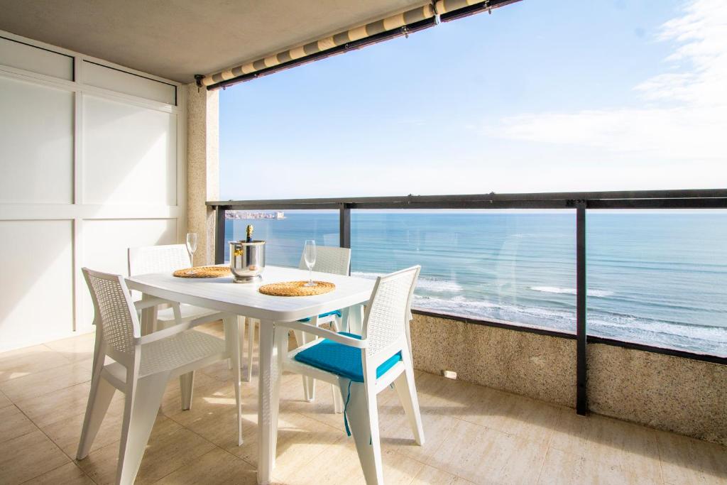 - une table et des chaises blanches dans une chambre avec vue sur l'océan dans l'établissement ESPACIO 18 - Primera Línea de Playa, à Cullera