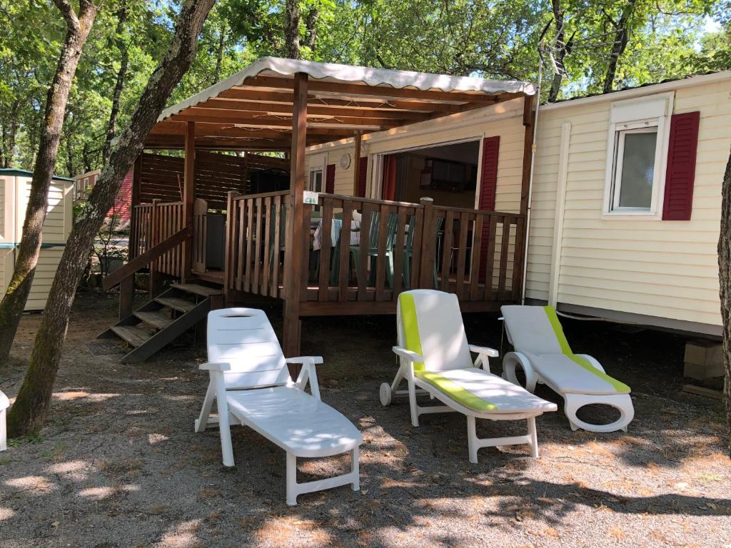 une cabine avec deux chaises et une terrasse couverte avec une terrasse dans l'établissement Mobil home Aluna Vacances camping Sunêlia, à Ruoms