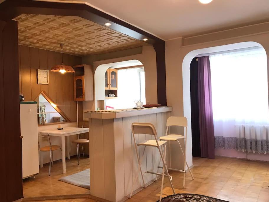 a kitchen with a counter and chairs in a room at Erdvus butas su balkonu šalia ežero ir stadiono in Visaginas