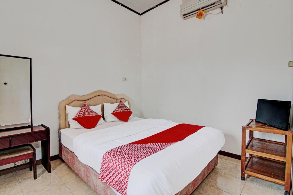 a bedroom with a bed with red pillows on it at OYO 92331 Rindu Sempadan Cottage in Pekanbaru