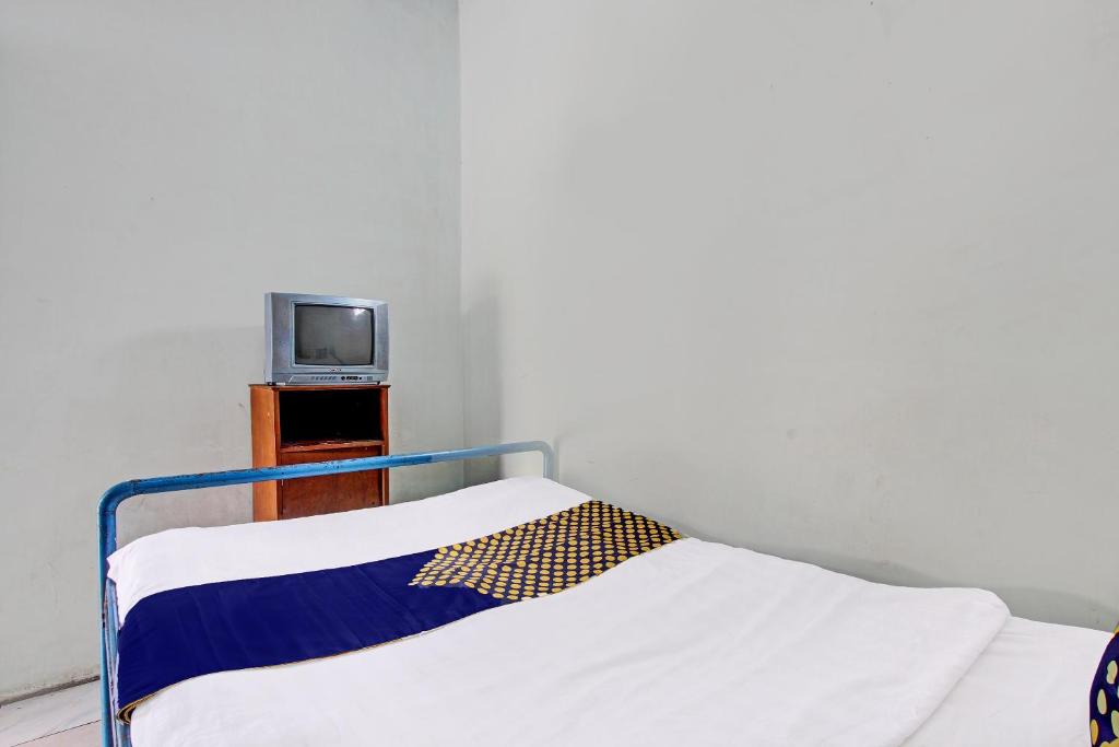 uma cama num quarto com uma televisão sobre uma mesa em SPOT ON 92336 Hotel Sukowati em Surakarta