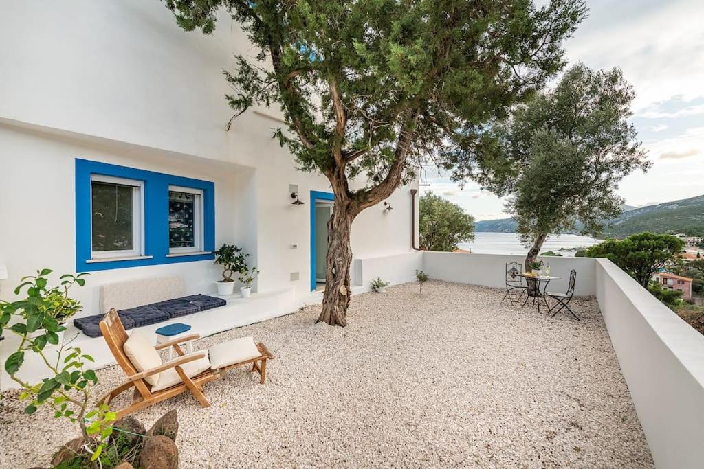 a patio with a tree and a table and chairs at AffittaSardegna-Casa Altamarea in Cala Gonone