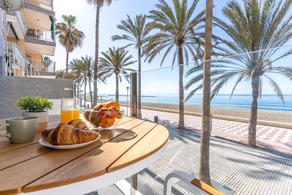 un tavolo con un cesto di frutta e un bicchiere di succo d'arancia di Expoholidays- Apartaments Paseo Marítimo a Almería