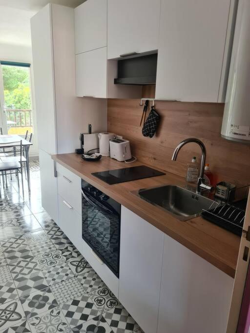a kitchen with white cabinets and a sink at Appartement Cosy Saint Cyprien in Saint-Cyprien