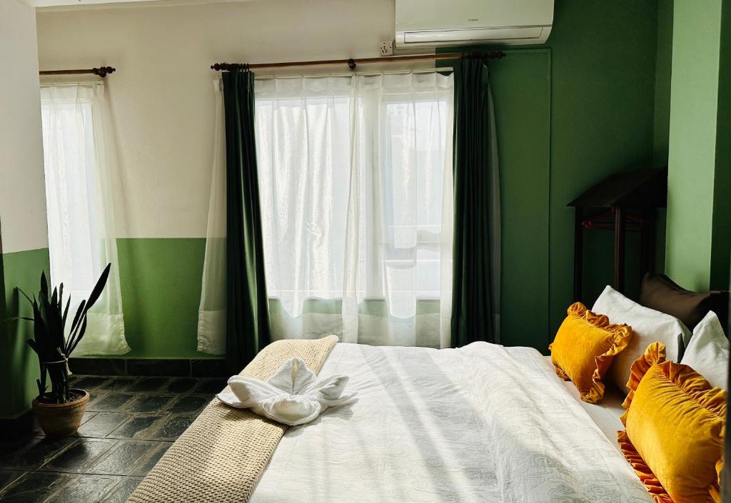 zieloną sypialnię z łóżkiem z białym kwiatem w obiekcie Hotel Darwin w Katmandu