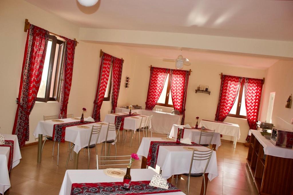 a restaurant with white tables and chairs and red curtains at Casa Amizade B&B in Pedra Badejo