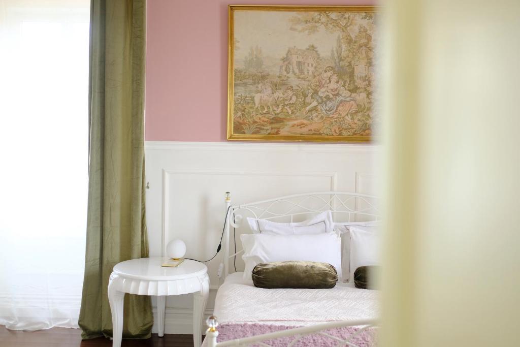 a white bedroom with a bed and a picture on the wall at Villa Várzea - Garden Suite in Várzea