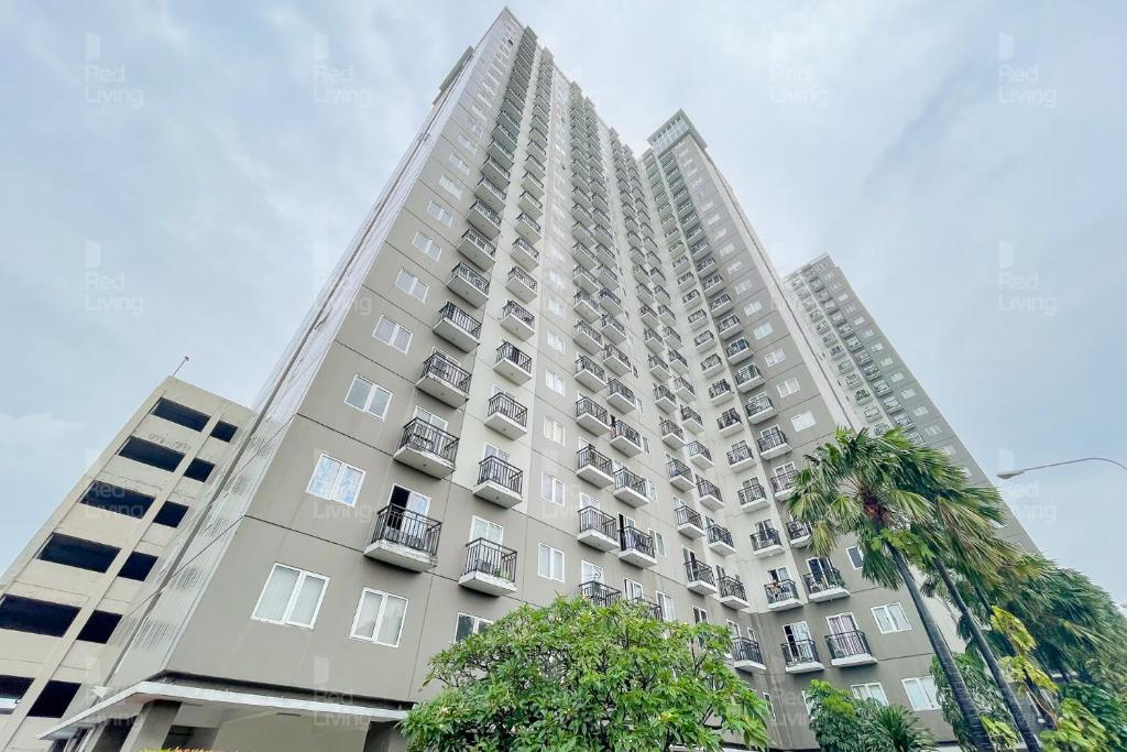 un edificio alto con una palmera delante de él en RedLiving Apartemen Sunter Park View - Emma Rooms, en Yakarta