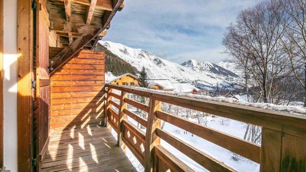 a wooden balcony of a cabin with snow covered mountains at Les Grizzlis - 27 - Appart vue montagne - 6 pers in Saint-Sorlin-dʼArves