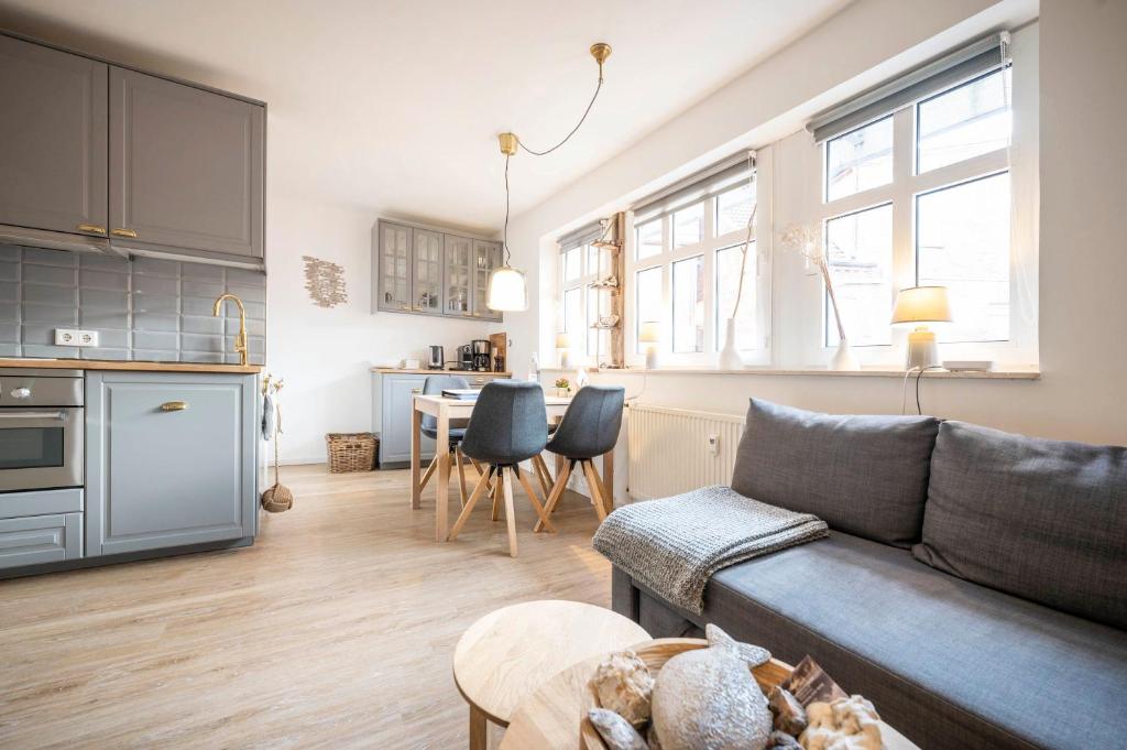 a living room with a couch and a kitchen with a table at Deine Juist Ferienwohnung Strandburg Juist in Juist