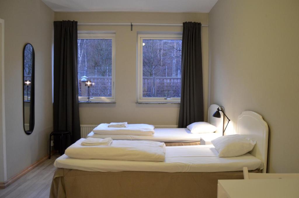 two beds in a room with two windows at Göteborgs Bed & Breakfast in Gothenburg