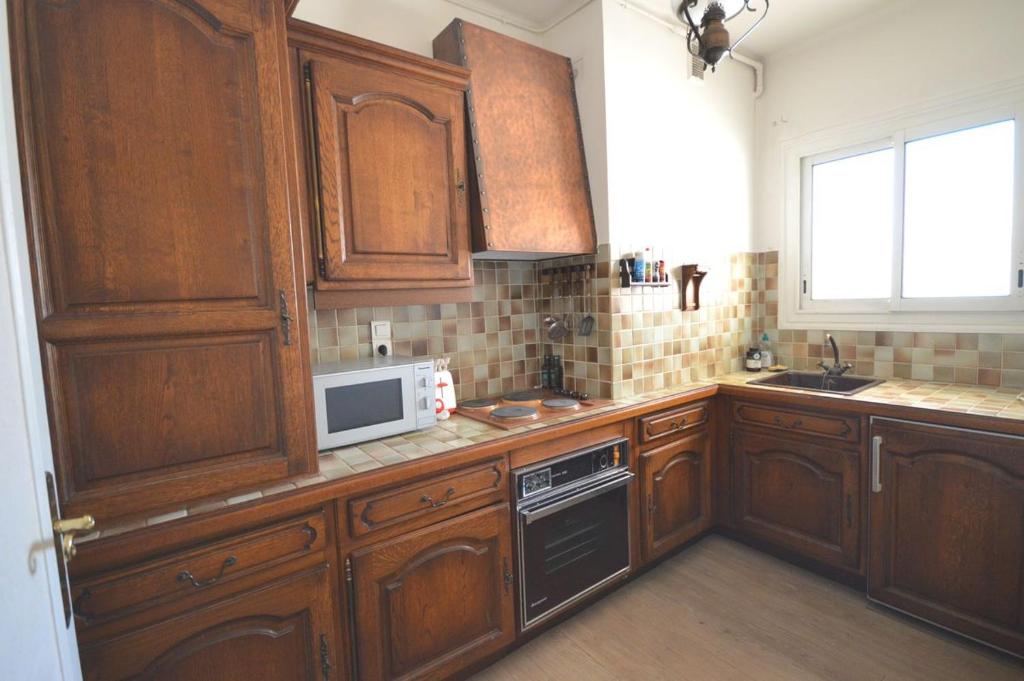 kuchnia z drewnianymi szafkami i mikrofalówką w obiekcie Studio Stanislas any comfort w Cannes