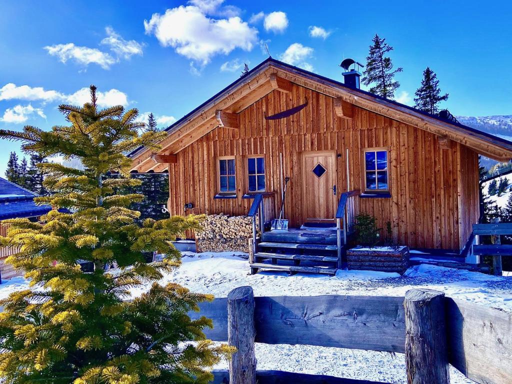 una cabaña de madera en la nieve con un pino en Holzknechthütte, en Lachtal